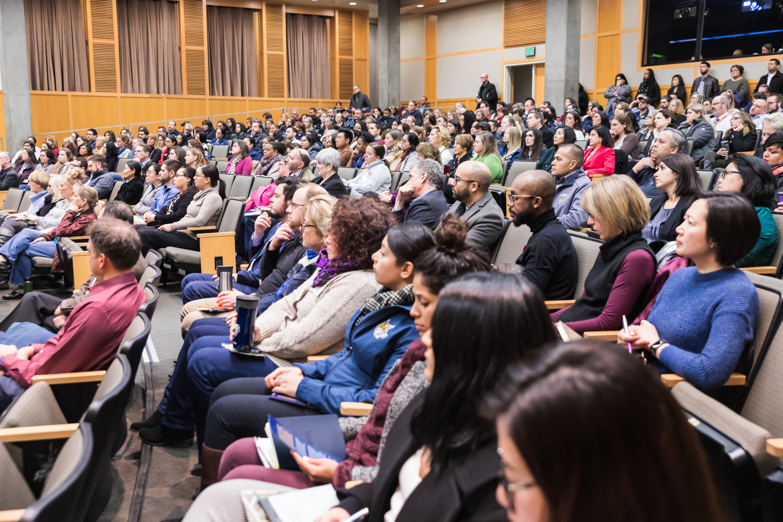 UC Merced staff sitting in an auditorium and pay attention, facing the stage area.